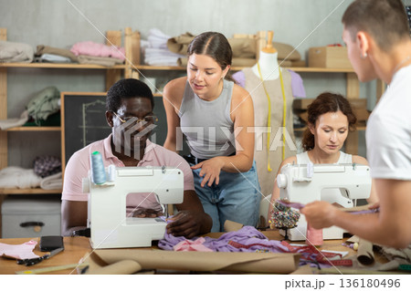 Young seamstress mentoring fashion students in garment construction class Young seamstress mentoring fashion students in garment construction class 136180496
