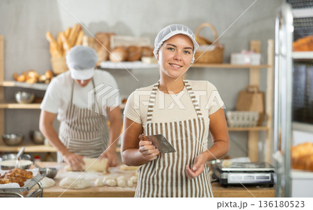 Young female baker holding a dough cutter in bakery 136180523
