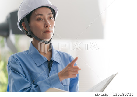 図面を確認する作業着の女性 図面を確認する作業着の女性 136180710