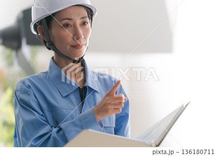 図面を確認する作業着の女性 136180711