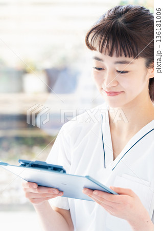 スクラブを着て窓辺に立つ医療従事者の女性 136181006