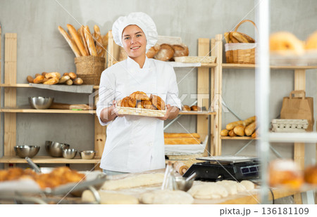 Young woman are standing in kitchen with basket of finished products croissant 136181109