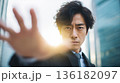 光に向かって手を伸ばし、何かを掴もうとする日本人男性 136182097