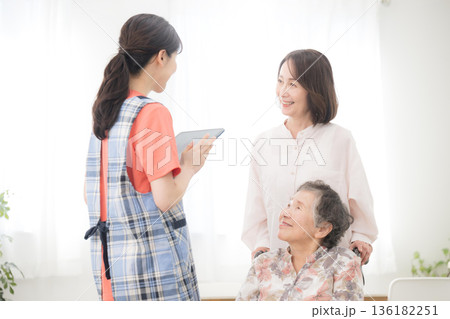 在宅介護や訪問介護のデイサービスのイメージで訪問する看護師と後期高齢者の女性と家族　訪問介護の計画 136182251