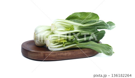Fresh bok choy vegetables arranged on a wooden board against a white background 136182264