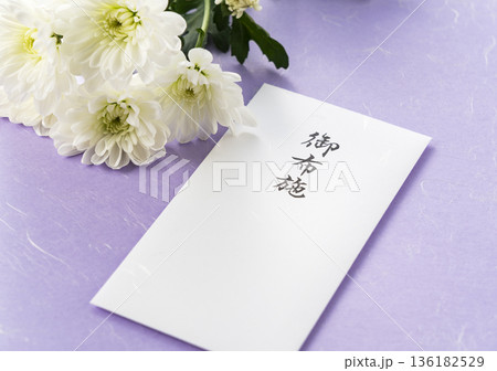 紫色の和紙を背景にした白い菊の花と「御布施」の封筒(仏事・葬儀イメージ) 紫色の和紙を背景にした白い菊の花と「御布施」の封筒(仏事・葬儀イメージ) 136182529
