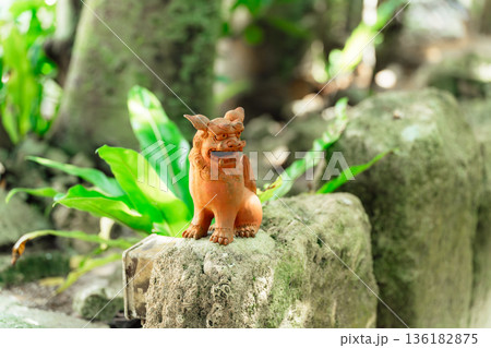 新緑を背景に佇む沖縄の守り神・シーサーの置物 136182875