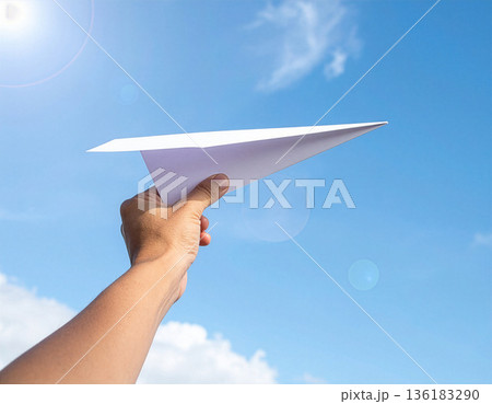 Hand launching a paper airplane into the sky, free 136183290