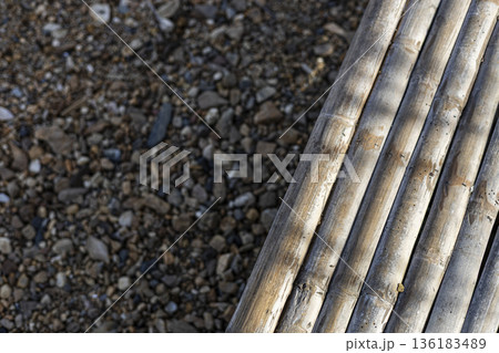 Bamboo Slat Bench For Shade, A top-down photo of bamboo slat, simple wooden slats resting on smooth pebble floor, for garden relaxation or minimalist outdoor documentary. Bamboo Slat Bench For Shade, A top-down photo of bamboo slat, simple wooden slats resting on smooth pebble floor, for garden relaxation or minimalist outdoor documentary. 136183489