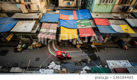 Aerial View Of Red Scooter Delivering In A Colorful City Street With Various Awnings And Buildings 136184485