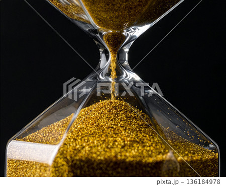 黒い背景で流れる金色の砂のあるモダンな砂時計のクローズアップ、時間管理のコンセプト 136184978