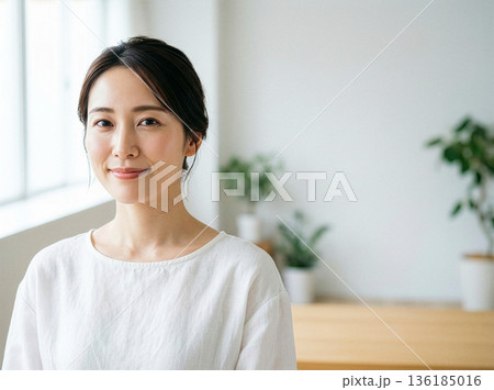 柔らかな自然光の室内で微笑む女性のナチュラルポートレート、シンプルで健康的なライフスタイル 136185016