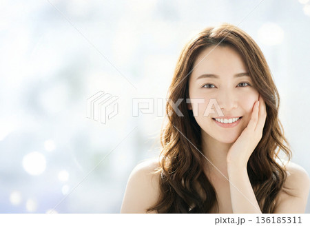 明るい光の中で頬に触れ微笑む女性のナチュラルな美肌、スキンケアと美容コンセプト 136185311