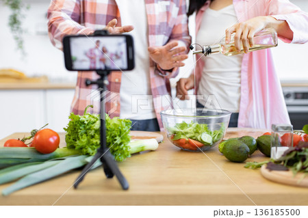 A couple prepares a healthy salad in their kitchen while recording a video for their online audience 136185500