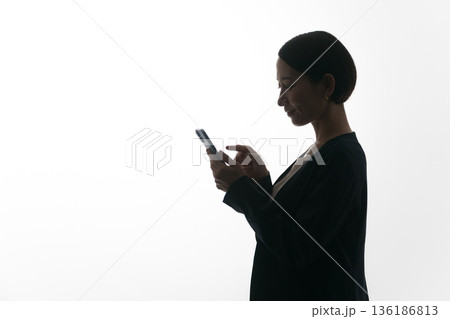 スマホを見る女性の横顔のシルエット スマホを見る女性の横顔のシルエット 136186813