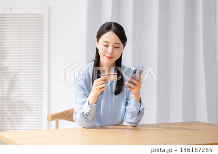 クレジットカードを見ながらスマホを操作する女性 136187285