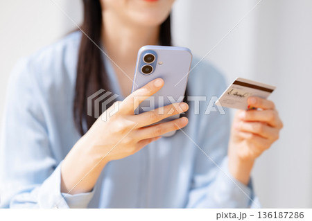 クレジットカードを見ながらスマホを操作する女性 136187286