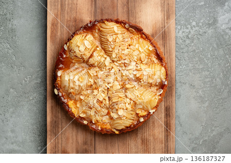 Freshly baked apple tart on a wooden board with almond slices on top 136187327