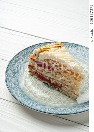 Slice of cake on patterned plate with wooden table background 136187373