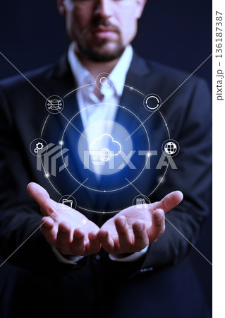 Business person holds cloud computing symbols in hands at night 136187387