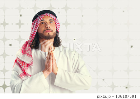 Man praying during Ramadan while wearing traditional clothing and looking upwards Man praying during Ramadan while wearing traditional clothing and looking upwards 136187391
