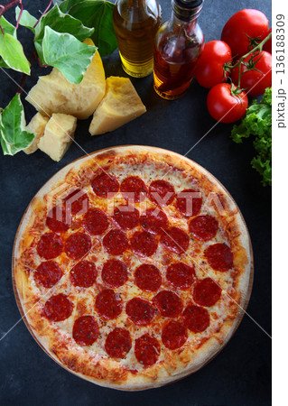 Classic pizza with spicy pepperoni sausage. A popular filling. Pieces of hard cheese are laid out on the table. Top view. Classic pizza with spicy pepperoni sausage. A popular filling. Pieces of hard cheese are laid out on the table. Top view. 136188309