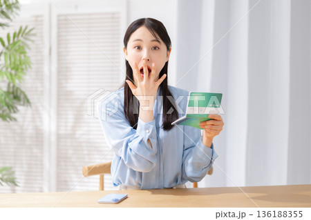 通帳を持って驚く女性 136188355