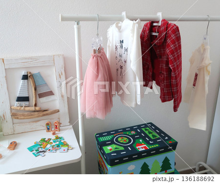 Clothes on hanger and little girl toys in room. Study area. Education and materials. Modern-style furniture and items.  136188692