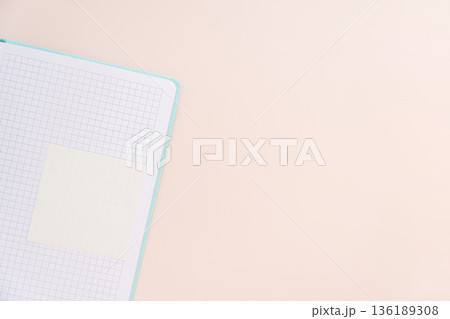 Grid notebook corner with sticky note and copy space, soft pastel background 136189308
