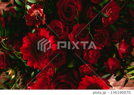 Dense cluster of deep red carnations creates dramatic texture. Moody floral design, gothic romance, dramatic floral arrangement. 136190070