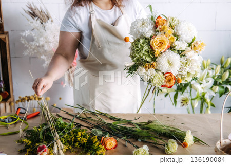 Creative entrepreneur holds lush flower bouquet in bright florist studio. Women in business, boutique owner, small business growth. Creative entrepreneur holds lush flower bouquet in bright florist studio. Women in business, boutique owner, small business growth. 136190084