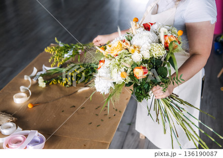 Florist demonstrates bouquet assembly during botanical art education session. Community workshop, florist teaching, experiential marketing. 136190087