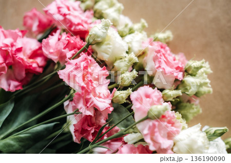 Pink and white lisianthus flowers rest in close up view on neutral surface. Floral design process, creative workspace, artisanal skills, flower workshop. 136190090