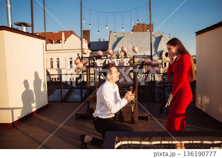Couple celebrates engagement on a rooftop with city view during sunset in a joyful moment of love and happiness Couple celebrates engagement on a rooftop with city view during sunset in a joyful moment of love and happiness 136190777