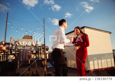 Couple shares a special moment on a rooftop during sunset in a city setting 136190778