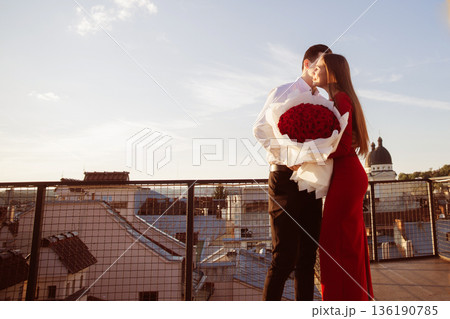 Couple shares a moment on rooftop with roses during sunset in city skyline scene Couple shares a moment on rooftop with roses during sunset in city skyline scene 136190785