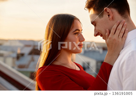 Couple sharing a tender moment during sunset on a rooftop in the city while enjoying their time together Couple sharing a tender moment during sunset on a rooftop in the city while enjoying their time together 136191005