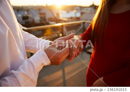 Couple exchanges rings during sunset on a rooftop in an urban area Couple exchanges rings during sunset on a rooftop in an urban area 136191015