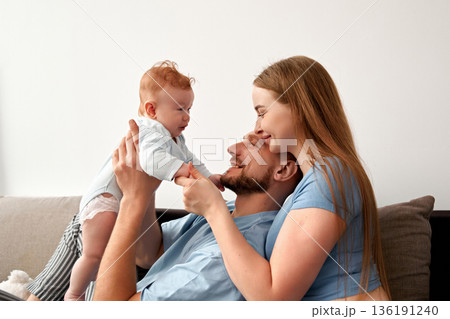 Joyful family moments with parents and baby sharing laughter and love in a cozy living room setting creating a warm family bond concept 136191240