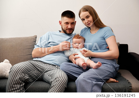 Family portrait with parents holding baby on couch in cozy living room showcasing love and connection in a nurturing environment family bonding concept Family portrait with parents holding baby on couch in cozy living room showcasing love and connection in a nurturing environment family bonding concept 136191245