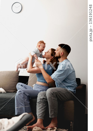 Joyful family moment with parents playing and bonding with their baby in a cozy living room setting showcasing love and connection family bonding concept 136191248