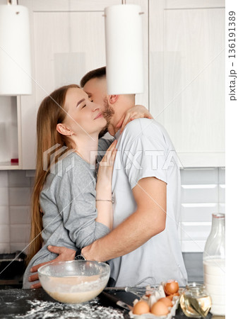 Couple Sharing a Joyful Moment While Cooking Together in a Modern Kitchen During a Sunny Afternoon Couple Sharing a Joyful Moment While Cooking Together in a Modern Kitchen During a Sunny Afternoon 136191389
