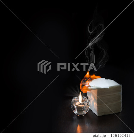A burning candle lit the napkins on the table A burning candle lit the napkins on the table 136192412