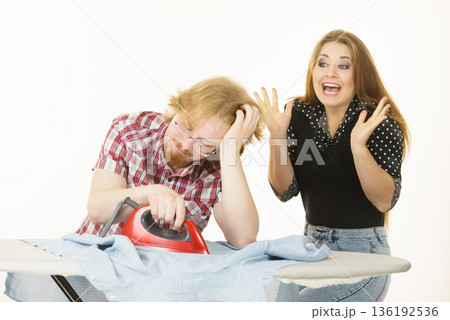 Happy woman and bored man ironing clothes Happy woman and bored man ironing clothes 136192536