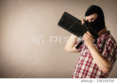 Man in balaclava holding keyboard and gun Man in balaclava holding keyboard and gun 136192538