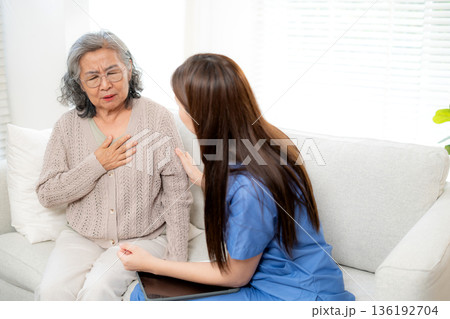 Asian woman nurse checking senior patient with chest pain, elderly woman having breathing problem. 136192704