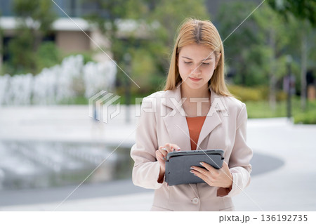 Young caucasian businesswoman writing on digital tablet in city. 136192735