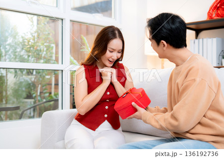 Happy asian man giving heart gift box to girlfriend celebrating Valentine's Day or anniversary. 136192736