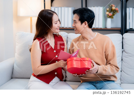 Asian young man and girlfriend celebrating Valentine's Day, woman holding card and gift box. 136192745