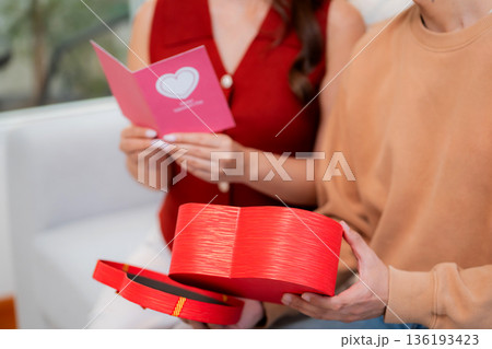 Asian young man and girlfriend celebrating Valentine's Day, woman holding card and gift box. Asian young man and girlfriend celebrating Valentine's Day, woman holding card and gift box. 136193423